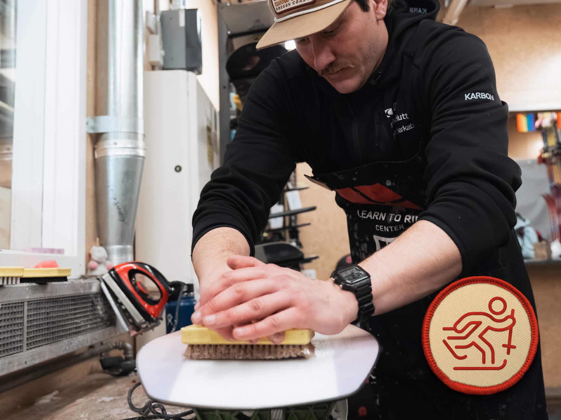 Person waxing or tuning a snowboard in the Mt Hutt Ski Workshop.