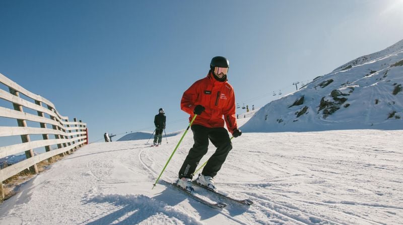 Ski instructor demonstrating a turn during a lesson on a groomed slope at Mt Hutt ski field