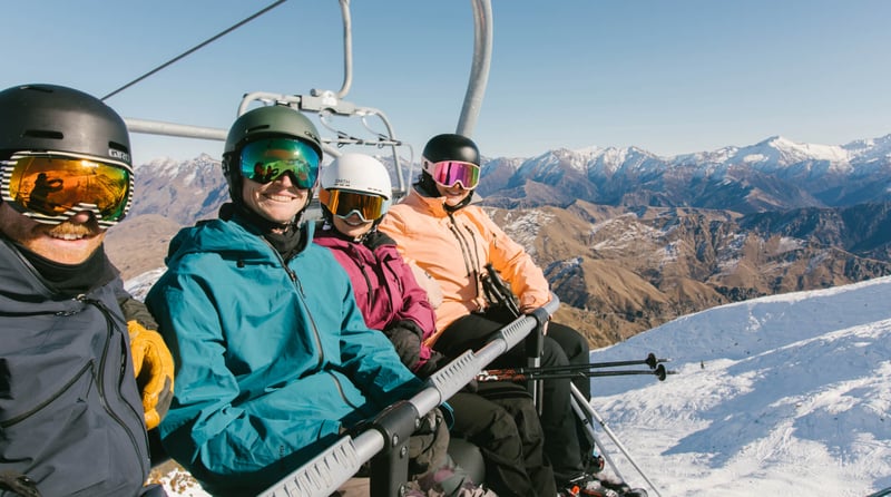 Group of skiers riding a chairlift at Mt Hutt with alpine mountain views in the background