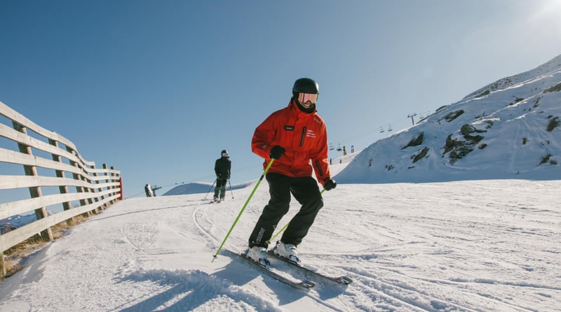 Ski instructor demonstrating a turn during a lesson on a groomed slope at Mt Hutt ski field